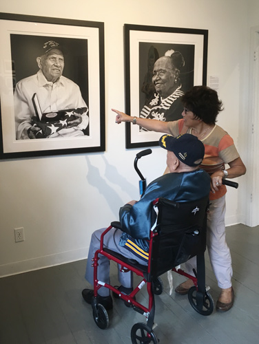 Filipino WW2 veteran and Purple Heart recipient Patricio Ganio looking at his portrait at The Yellow House Gallery