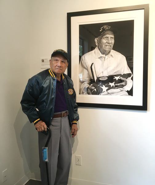 Filipino WW2 veteran and Purple Heart recipient Patricio Ganio standing next to his portrait